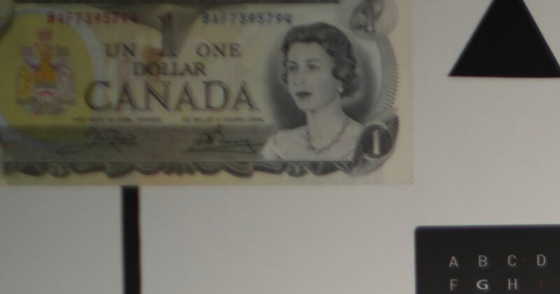 A Canadian one-dollar bill featuring a portrait of a woman, partially placed over a white background with black geometric shapes and letters.