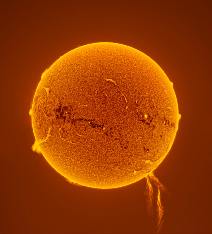 A close-up image of the Sun shows a glowing orange sphere with visible dark spots, swirling textures, and bright, fiery prominences extending from its surface against a dark background.