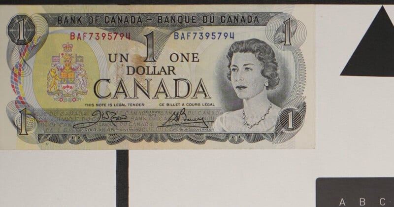 A Canadian one dollar bill featuring a portrait of Queen Elizabeth II, text in English and French, and the coat of arms of Canada on the left side. Serial number BAF7395794 is visible.