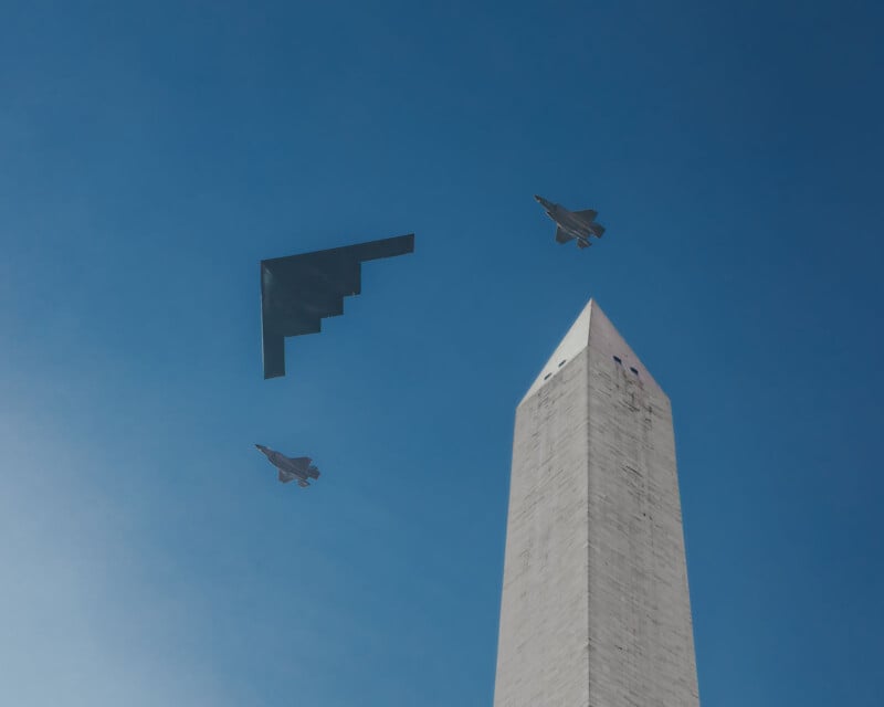 A stealth bomber and two fighter jets fly past the Washington Monument against a clear blue sky.