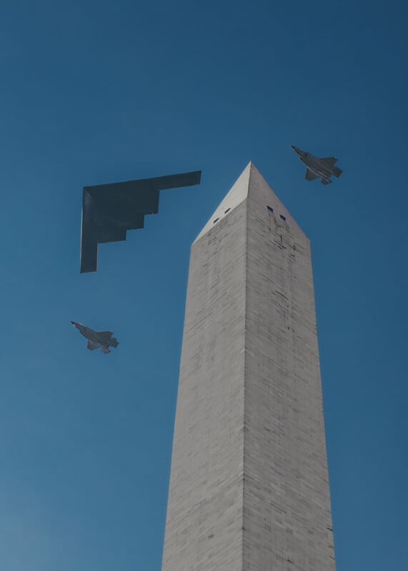Three military aircraft, including a stealth bomber and two fighter jets, fly past the Washington Monument against a clear blue sky.