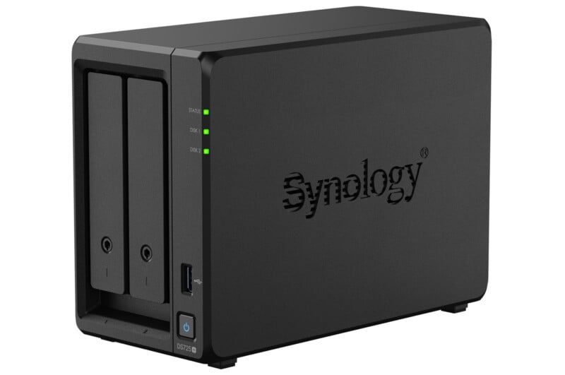 A black Synology network-attached storage (NAS) device, featuring two drive bays, indicator lights, a USB port, and a power button on the front panel. The Synology logo is visible on the side.