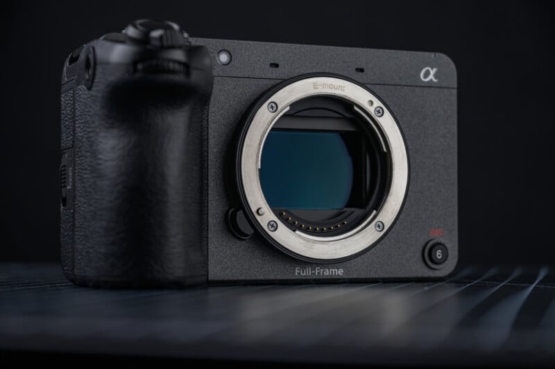 A close-up of a black Sony full-frame mirrorless camera body without a lens, displaying its E-mount and image sensor, against a dark background.