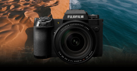 A Fujifilm camera with a Fujinon aspherical lens is displayed against a scenic background of sandy dunes meeting the ocean.
