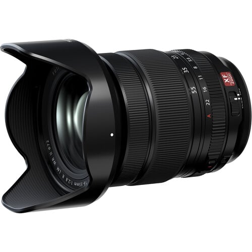 A wide-angle Fujinon XF 16-55mm f/2.8 R LM WR camera lens with a petal-shaped lens hood, black body, red and white markings, and textured zoom and focus rings.