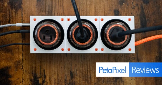 A top-down view of three modern electrical outlets with cords plugged in, mounted on a wooden surface. The Petapixel Reviews logo appears in the bottom right corner.