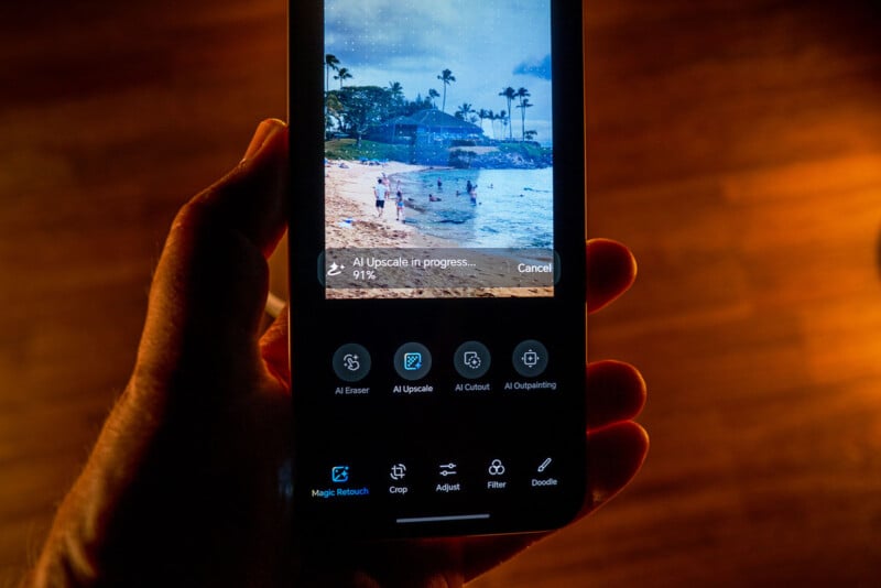 A hand holds a smartphone displaying a photo editing app, showing a beach scene being enhanced with AI upscaling. The app interface shows progress at 91% with various editing options visible below the photo.