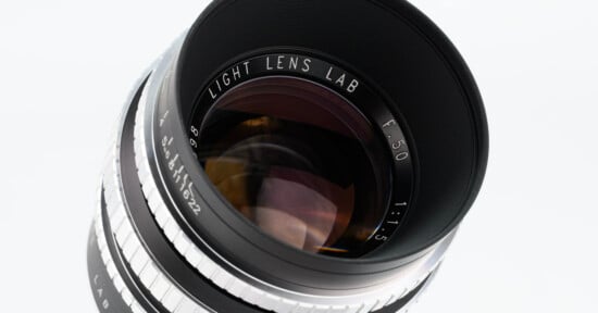 A close-up view of a camera lens labeled "Light Lens Lab F50 1:1.5" with silver and black details, showing reflections on the glass elements.