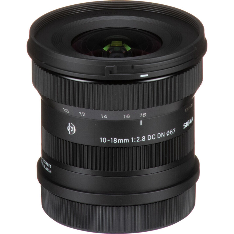 A Sigma 10-18mm f/2.8 DC DN camera lens with a wide-angle design. The lens features focus and zoom rings, distance markings, and a 67mm filter thread. It has a black finish and compact size, ideal for photography enthusiasts.