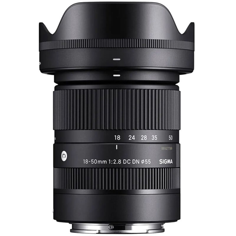 A Sigma 18-50mm f/2.8 DC DN camera lens with a sleek black design, featuring zoom and focus rings, and marked with focal lengths and brand details. The lens has a petal-shaped hood attached.