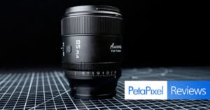 A black 85mm f/1.4 camera lens sits upright on a grid-patterned surface, with the text "Petapixel Reviews" in blue and white in the lower right corner.