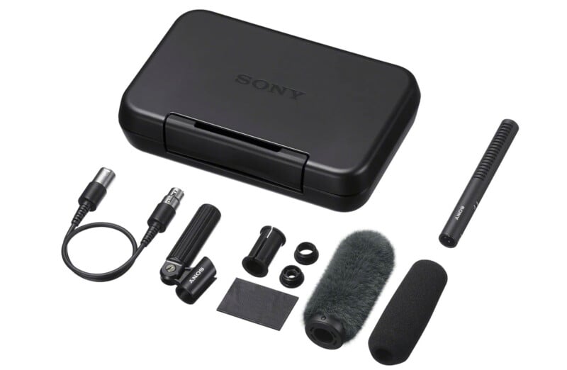 A Sony microphone kit including a black carrying case, shotgun microphone, windscreen, foam cover, cables, adapters, mic clip, and mounting accessories arranged on a white background.